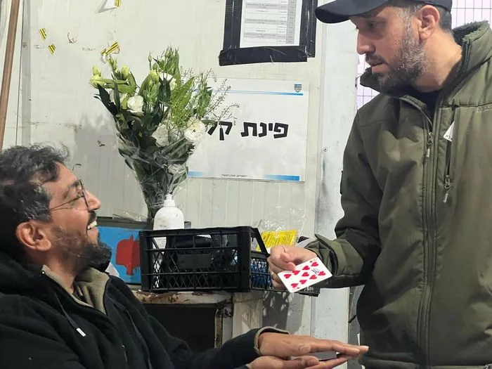 Tomer Khafif performing a sleight-of-hand trick for soldiers.